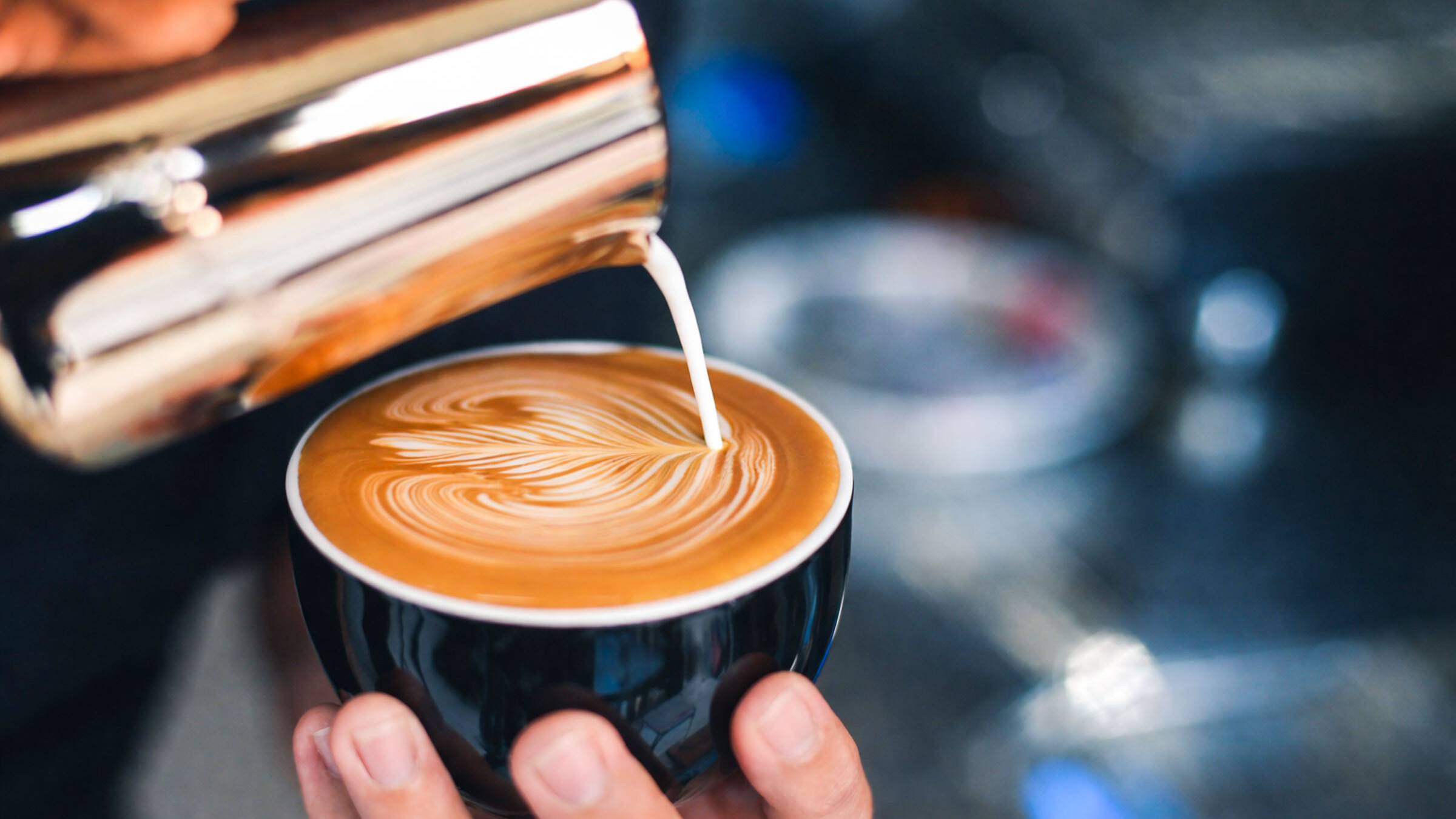 Barista bereitet Cappuccino für Firmenevent mit Latte Art zu